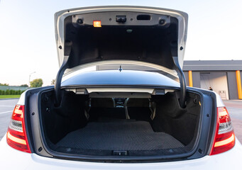 The open car trunk showcases a spacious interior with a plush carpeted floor, designed for...