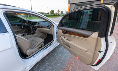 Experience the luxurious interior of a white sedan, featuring elegant beige upholstery and an open...