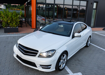 A stunning White MercedesBenz Coupe is parked at a modern venue, showcasing its futuristic design...