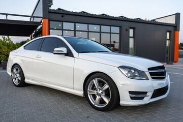 A sleek and stylish white luxury sedan is gracefully parked in a contemporary urban setting, making...