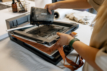 Manual Silk Screen Printing on Fabric – Close-up of Hands Working with Screen Printing Machine in Workshop