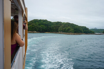 Tourists take a photo aboard a sightseeing boat in the Saikai National Park's Kujukushima Islands, also called the 99 Islands, in Sasebo, Nagasaki Prefecture, Japan 