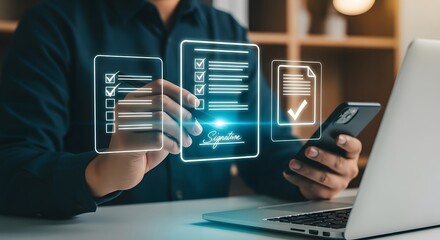 Man signs digital contract on phone with laptop nearby at office