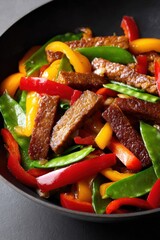 Wok containing delicious vegan meat with colorful peppers and snow peas