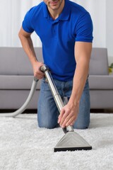 Cleaning service worker vacuuming white carpet in living room