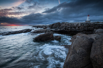 Lorient Morbihan Dark stormy clouds above waves smashing into jagged granite rocks.