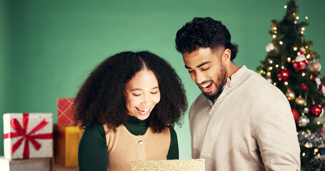 Christmas, gift and surprise with couple in studio for holiday season, celebration and xmas...
