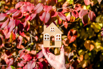 The symbol of the house in the girl's hand on the background of red leaves
