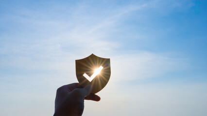 Wooden shield with checkmark cutout and sunlight passing through, symbolizing security, trust,...