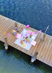 top view of romantic picnic on wooden pier over the lake with string light and air balloon