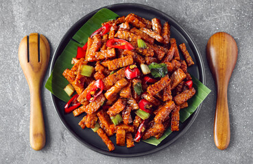 Tempeh or Tempe Orek. A dish featuring stir-fried tempeh strips, coated in a glossy, savory sweet...