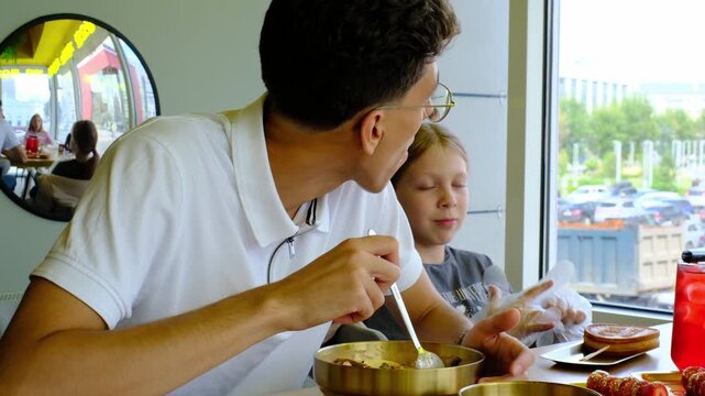 Young man with glasses enjoying a delicious meal in a modern dining setting, showcasing the progression of savoring flavors and engaging with food in a relaxed atmosphere