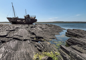 old wrecked sunken ship on the rocky shore of the Arctic Ocean is the