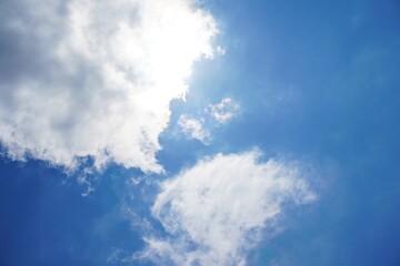 Background of sunlight through the clouds with a blue sky behind. Blue sky with clouds.one of the clouds partially covers the sun, a ray of sunlight breaks through because of a cloud