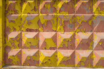 Close-up of a weathered painted metal surface with peeling blue and red paint on geometric embossed texture, useful for backgrounds, industrial design, urban decay, and creative grunge or vintage styl