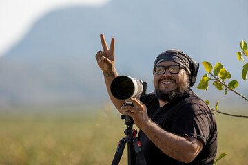 Professional photographer happy in a lush tropical landscape with his camera in the middle of the green landscape of the Costa Rican rainforest
