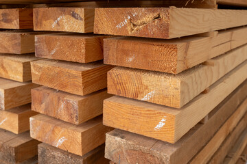 A close-up view of a neatly stacked pile of raw wooden planks, showing natural wood grain and textures, perfect for conveying themes of construction, natural materials, and craftsmanship