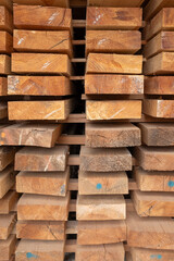Stacked wooden planks arranged for drying and storage, showing natural grain patterns, rough edges, and timber texture used in carpentry, construction, and woodworking