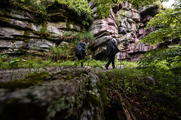 Hikers walking in the rain through narrow gorge in forest