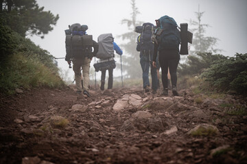 Hikers walking on rocky mountain trail in fog