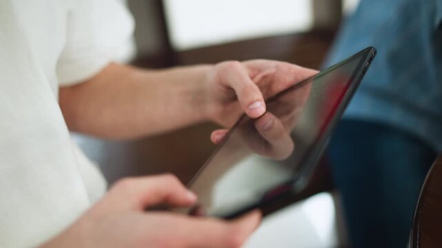White man wearing white polo tapping tablet screen highlighting sunlike symbol on thumbnail nails in modern workspace close up capturing fingertip gesture on touchscreen interface interaction