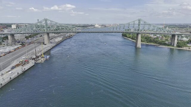 Drone flies north along the St. Lawrence River over the Jacques Cartier Bridge on a summer day in Montreal, Quebec, Canada