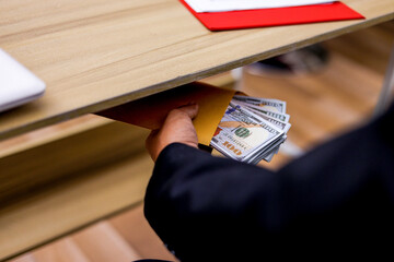 Businessman Conceals Bribe Money in Yellow Envelope Beneath Table