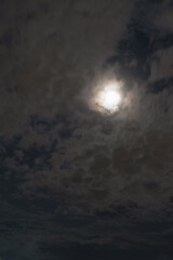 Moonlight shines through clouds in a night sky