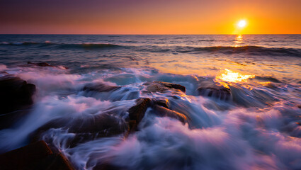 Naklejka premium Dramatic sunset over a rocky coastline with powerful ocean waves crashing against the shore creating a vibrant display of color and light