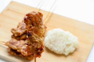 Hand holding one grilled pork skewers. Popular Thai food to eat for breakfast
