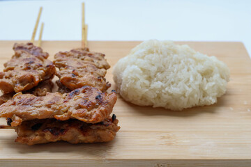 Front view of Grilled pork skewers and sticky rice on a wooden tray. Popular Thai food to eat for breakfast