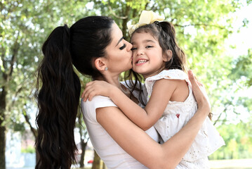 Naklejka premium Happy girl kid hugging mom in the nature