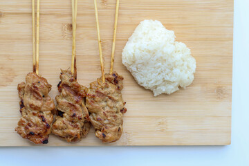 Top view of Grilled pork skewers and sticky rice on a wooden tray