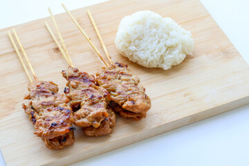 Grilled pork skewers and sticky rice on a wooden tray