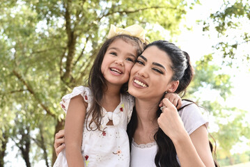 Naklejka premium Happy girl kid hugging mom in the nature