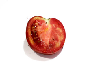 Close-up photo of a rotten tomato slice with flies on the surface, isolated on white background....
