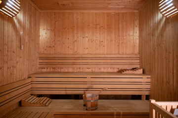 Empty Wooden Sauna Interior.Wide view of a warm and empty wooden sauna with rolled towels and...