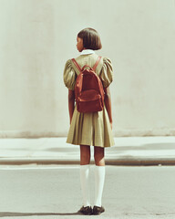 Young student in school uniform with backpack standing on street, back to school concept