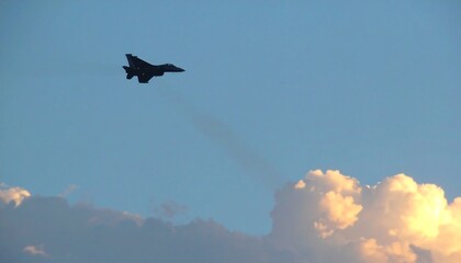 Silhouette of a fighter jet in flight, contrail visible
