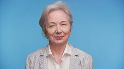 Confident senior woman smiling in studio portrait on blue - Powered by Adobe