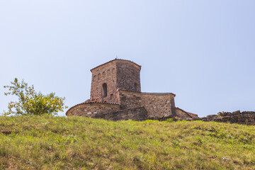 Ancient stone Serbian Orthodox church with cross tower on green hillside in Novi Pazar, Serbia,...