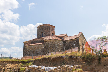 Medieval Serbian Orthodox church undergoing archaeological restoration with protective barriers and...