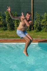 A man dives into the pool while making hand gestures