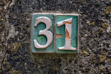 Numero civico 31 in ceramica antica su muro, stile tradizionale decorato, ideale per illustrare dettagli architettonici e atmosfere vintage.