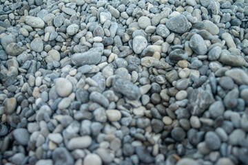 Smooth pebble stones scattered along a coastal shoreline, highlighting natural textures and seaside...