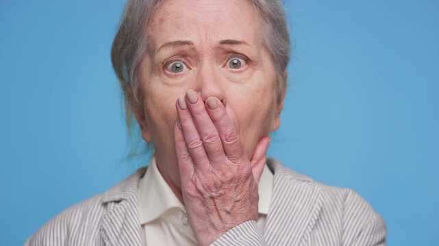 Shocked senior woman reacting to bad news on blue background
