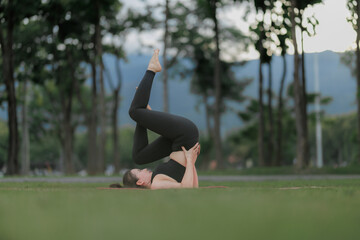 Calm and focused woman exercising yoga in a public garden, embracing relaxation and harmony with...