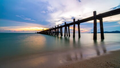 Fototapeta premium Serene sunset view of an old wooden pier extending into calm waters