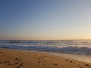 A sandy beach bathed in sunlight, touched by the sea, symbolizing vacation, relaxation, and summer escape.
