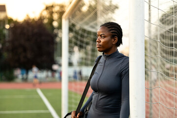 Black female goalkeeper on soccer training. Female goalkeeper standing by goal post and thinking about training.